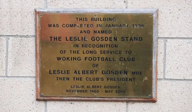 Biển tưởng niệm Leslie Gosden tại Kingfield Stadium, ghi nhận đóng góp quan trọng cho sự phát triển của Woking FC và sân vận động.