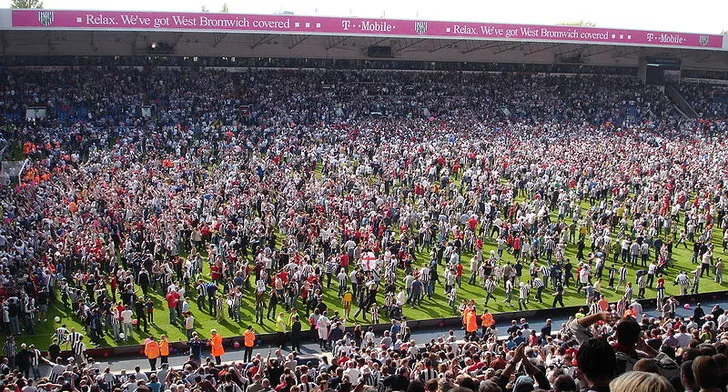 Cảnh tượng đám đông cổ động viên West Bromwich Albion ăn mừng sau sự kiện &quot;The Great Escape&quot;, thể hiện niềm đam mê cuồng nhiệt tại The Hawthorns, một cột mốc lịch sử của bóng đá Anh.