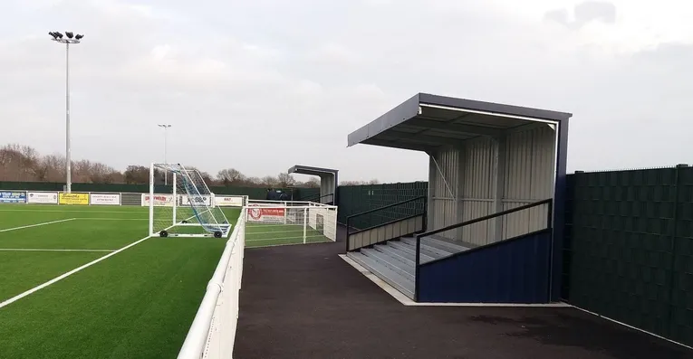 Khu vực khán đài đứng phía sau khung thành tại sân Parkside, nơi người hâm mộ Aveley FC cổ vũ nhiệt tình